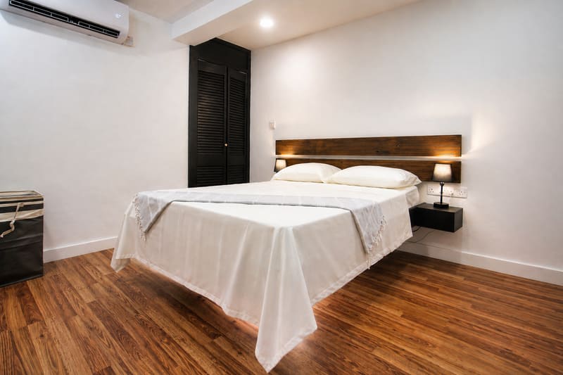 Bright bedroom at Il Blu Apartment with a wooden headboard, white linens and warm wood flooring